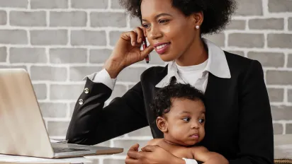 An african american business woman with baby working at home