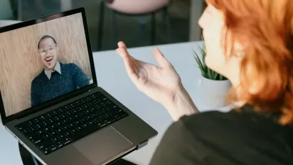 A woman talking to a man via a laptop