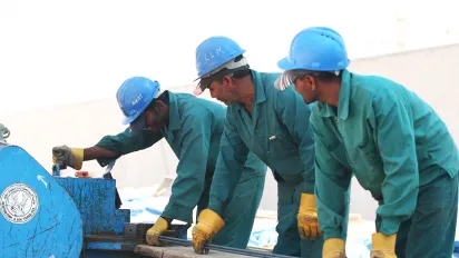 Foreign workers cut steel on a construction site in the UAE, 2021.